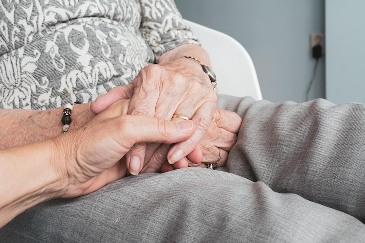 a person holding an older individual's hand
