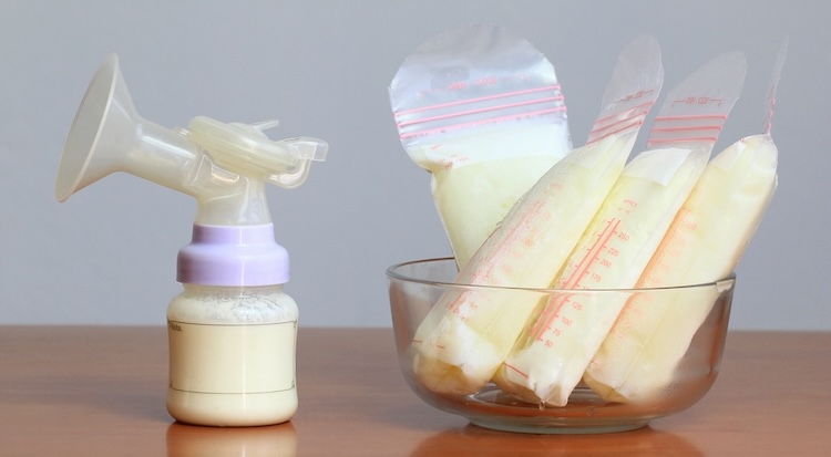 manual breast pump and bags of frozen human milk on table