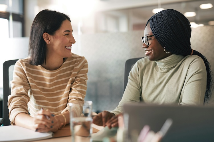 2 happy women chatting while sitting at table